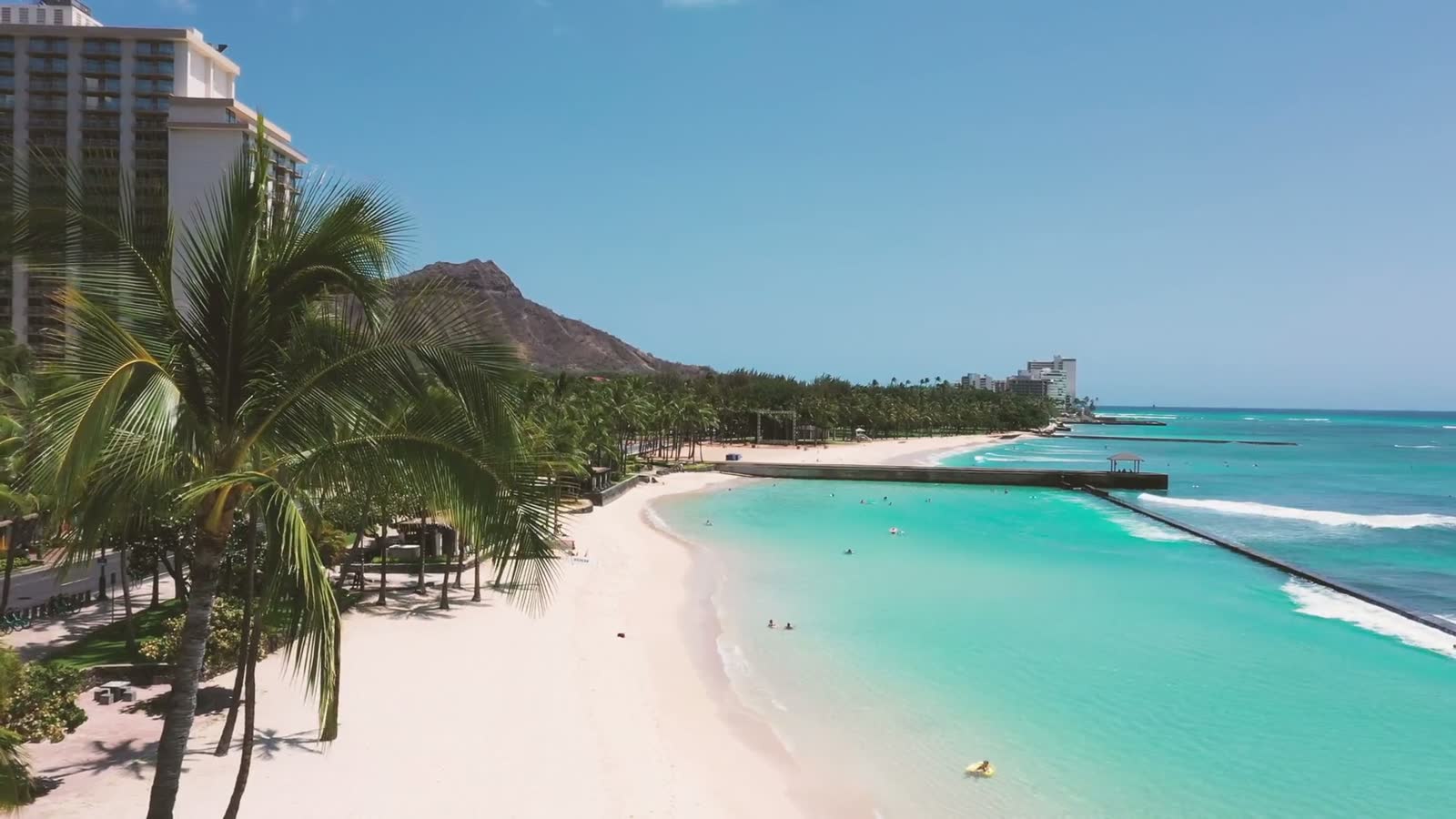 Palm trees lining Waikiki beach with Diamond Head in the distance