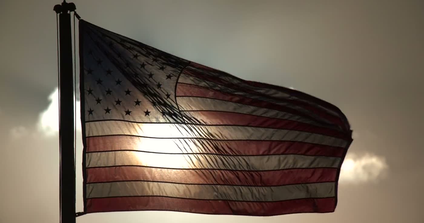 American flag waving against a bright sky